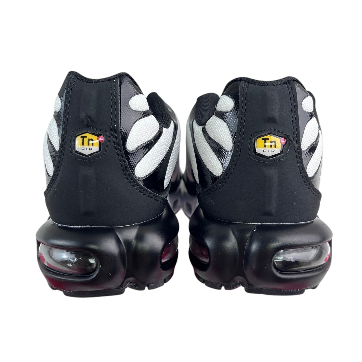 Luxury Chef Nike TN Air Max Plus sneakers in black with white accents and visible air cushioning. Iconic Tn Air logo on heel.